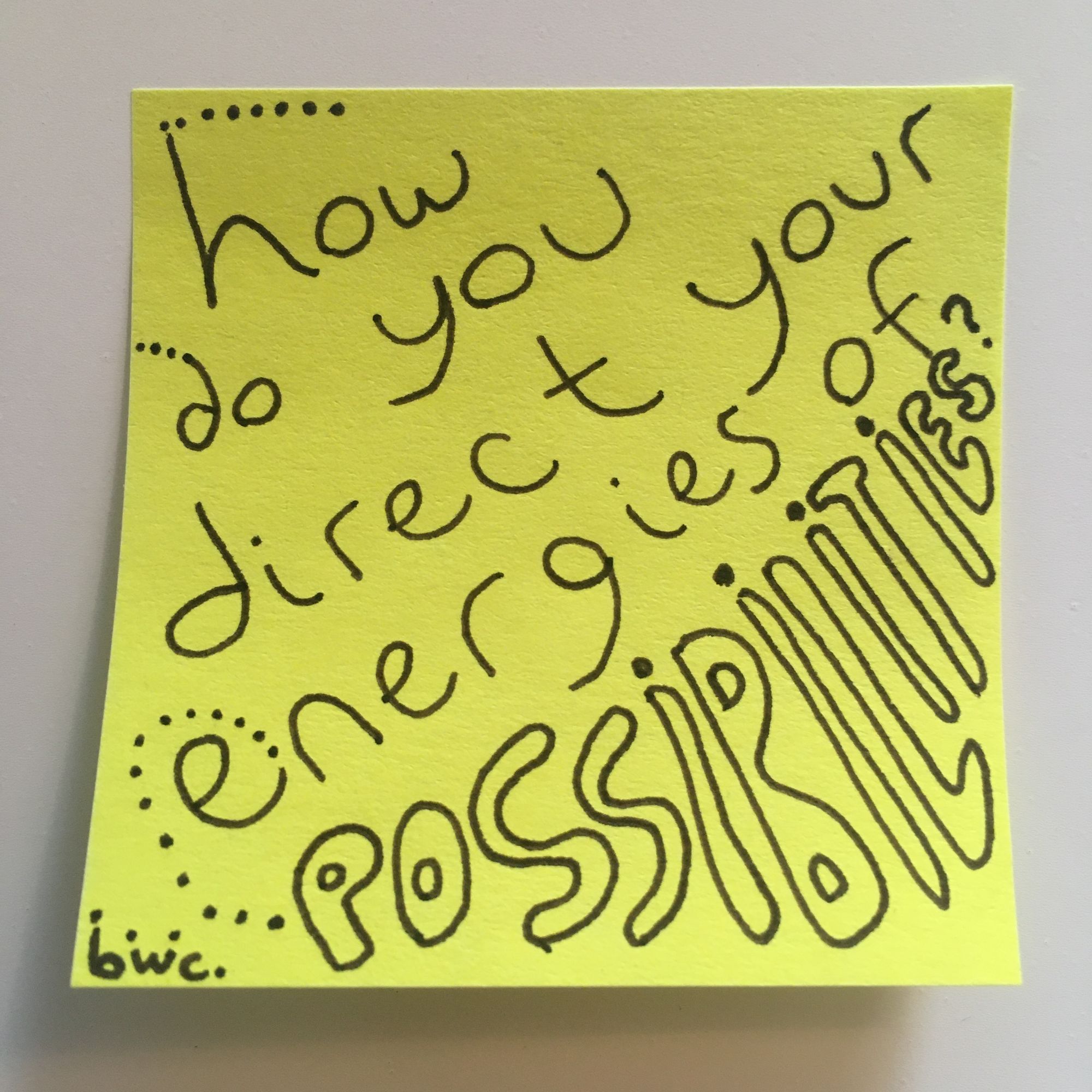 yellow square sticky note with handwritten message that says "how do you direct your energies of possibilities?" possibilities is in bold bubble letters and there are dots off several of the letters suggesting energy being sent out of the letters.
