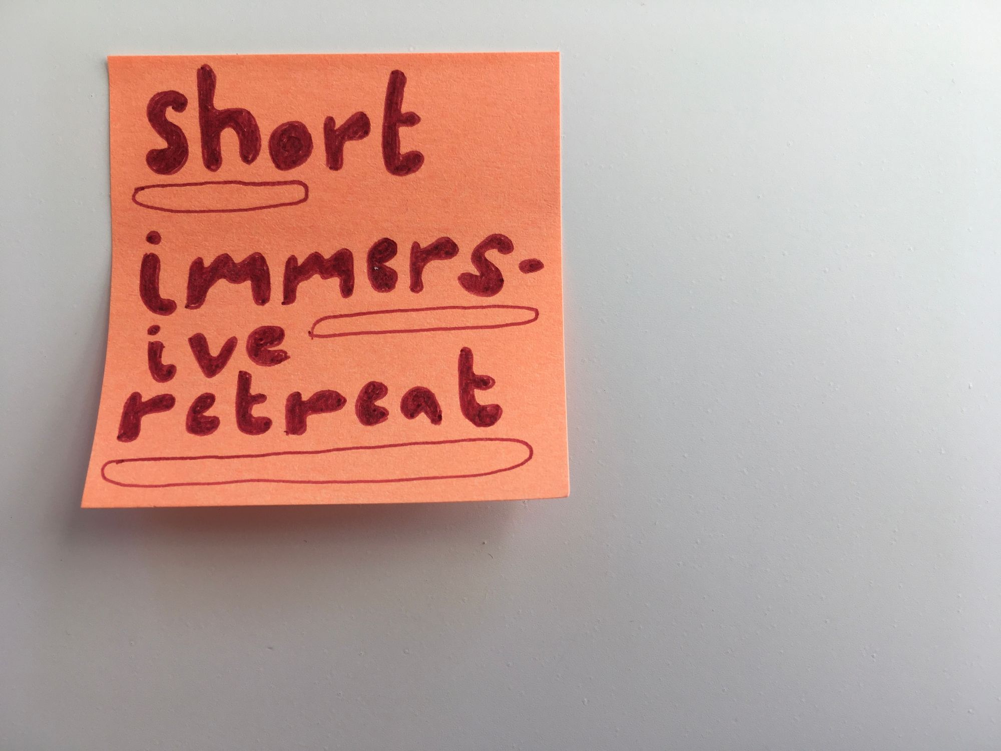 square orange sticky note stuck to upper right corner of white background with bubble letters handwritten: short (with a short bubble line drawn underneath), immers-ive (with a slightly longer bubble line drawn underneath) retreat (with a longer bubble ling drawn underneath)